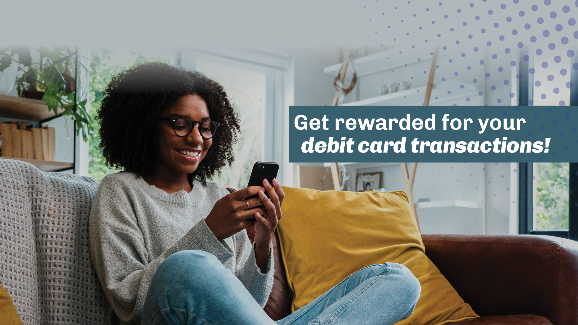 Get rewarded for debit card transactions. Woman sitting on couch, looking at her phone